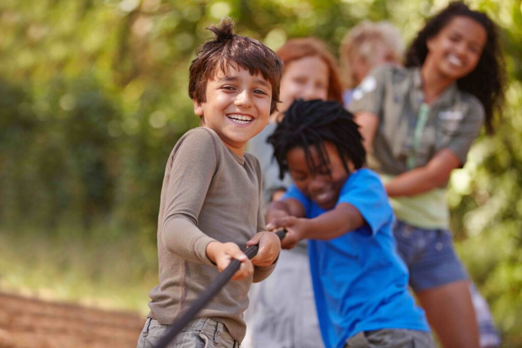 A group of children pulling together on a rope outdoors
