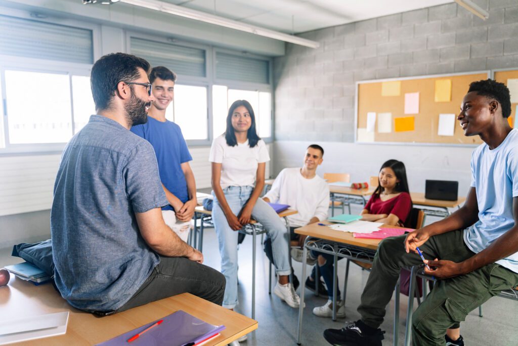 High school students in a group discussion with a teacher in a classroom